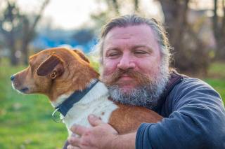 Man with beard hugging a dog
