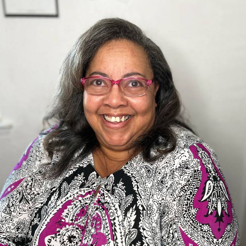 Image of Constance smiling wearing a purple and black patterned top